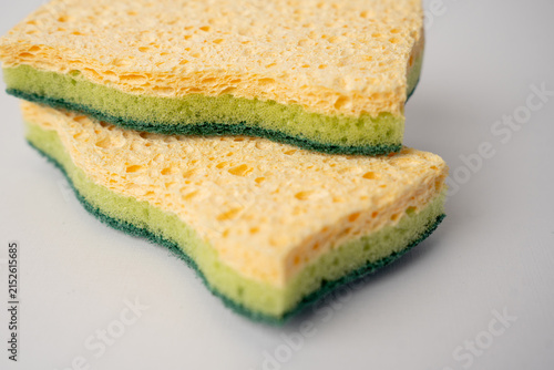 Two green and yellow kitchen sponges on white background.