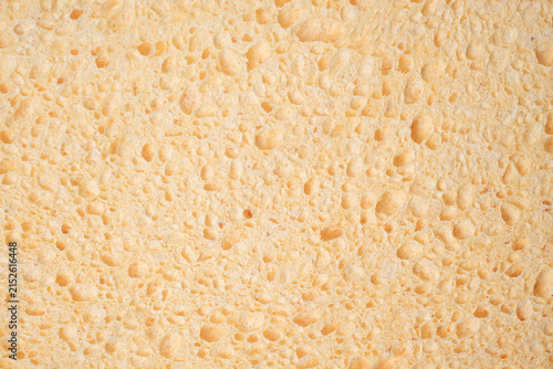 Yellow porous sponge texture macro background.