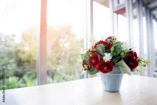 Artificial Flower Arrangement in Blue Pot on Table by Bright Window