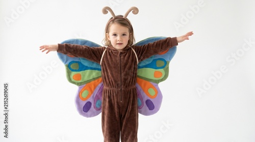 A young child dressed as a butterfly with wings spread wide, looking at the camera with a sweet expression.