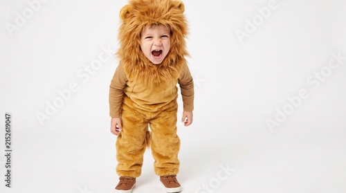A young boy dressed in a lion costume, with a fierce expression and mouth wide open, as if roaring. The costume is a tan color with a fluffy mane and tail
