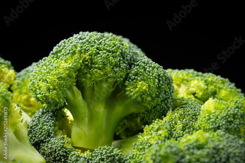 Close-up of a raw broccoli florets head on black background.
