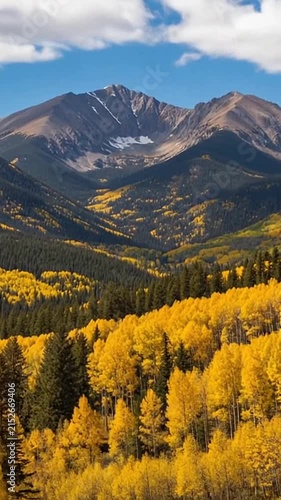 Stunning autumn mountain landscape with golden aspen trees and a majestic rocky peak under a clear blue sky