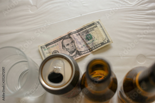 High Angle View of US Five Dollar Bill Behind Beer Bottles and Glass