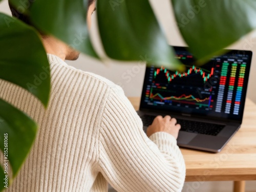 Hands typing on laptop with stock market analytics chart