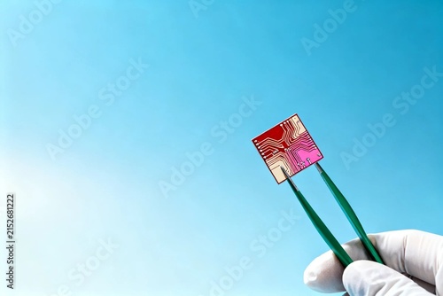 Microchip Held by Tweezers on Blue Background