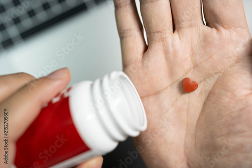 heart shaped pills over laptop workspace concept of heart care for overworked office employee. heart disease prevention, cardiovascular care, workplace stress, health supplements for overworked