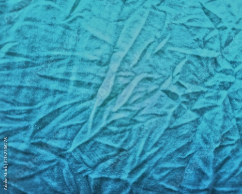 Close-up of cyan blue crumpled fabric texture background.