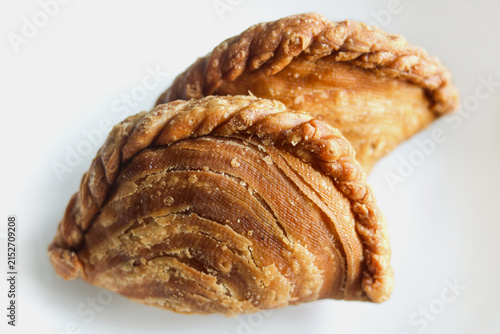 Bild auf Leinwand Two golden crispy spiral curry puffs with braided edges.