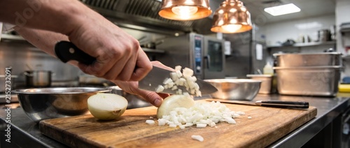 Professional chef hands dicing white onions on a wooden cutting board