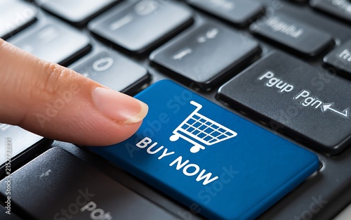 Finger pressing BUY NOW key on keyboard symbolizing e-commerce and digital purchasing convenience