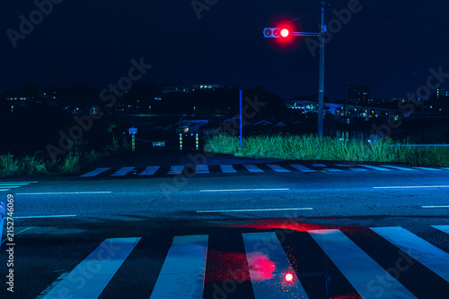 濡れた路面に赤信号が反射する青い夜の交差点