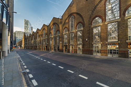 View of the historic brick facade of the former Billingsgate Market building with its distinctive arched windows and modern skyscrapers in London, England, United Kingdom.