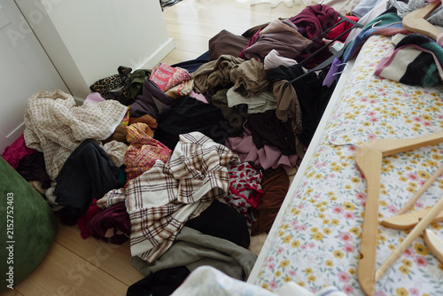 Foto Clothes scattered on the floor near a bed in the room