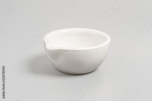 фотографія Clean studio shot of an empty white porcelain mortar bowl featuring a pouring spout, placed on a light grey background