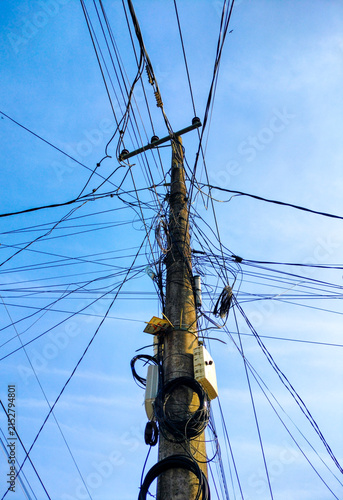Messy Tangled Power and Telecommunication Wires on Concrete Utility Pole