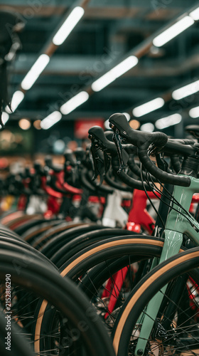 Bicycle Store Showcase: A row of colorful road bikes lined up in a brightly lit store, showcasing their sleek frames, handlebars, and wheel rims, ready for cycling enthusiasts.