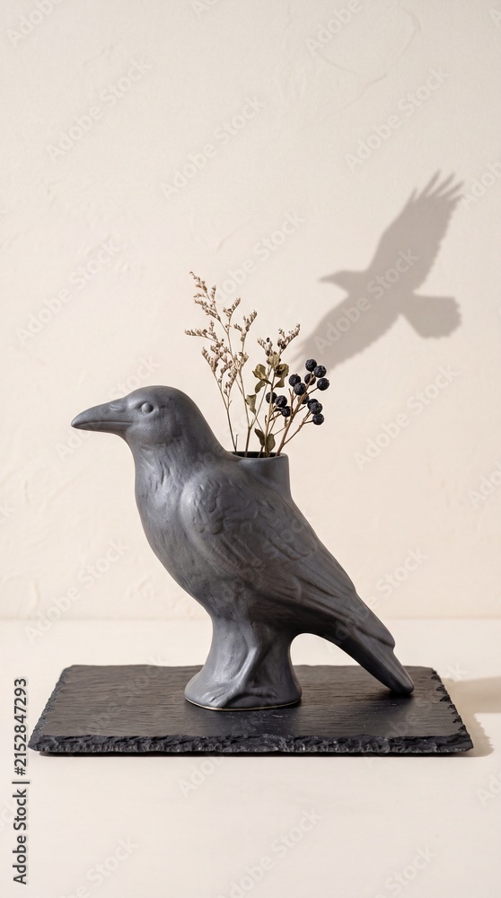 Obraz premium Decorative Raven Sculpture Vase Holding Dried Flowers With A Distinct Bird Shadow Casting On A Wall Creating Artistic Interior Design Decor Elements For Seasonal Home Ornamentation And Styling