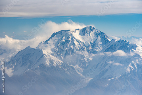 Aerial view of Nanga Parbat, the ninth highest mountain in the world, featuring snow-capped peaks, rugged glaciers, and surrounding clouds in the Himalayas, Gilgit-Baltistan, Pakistan.