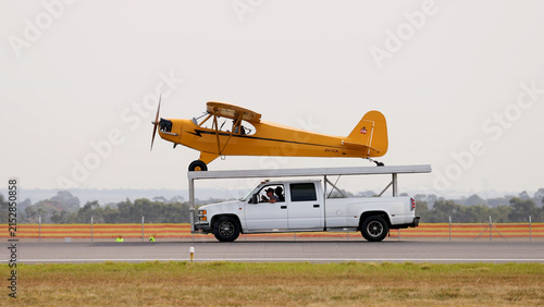 Foto Yellow Piper Cub Aircraft Mounted on a Moving Truck at Airshow