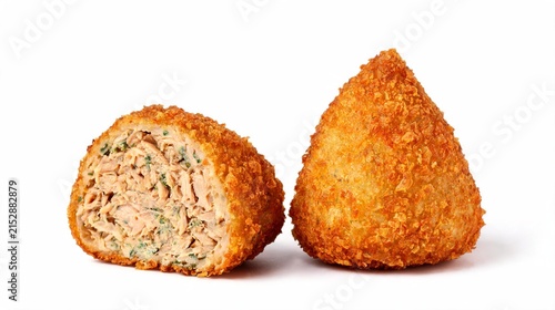 A crispy, deep-fried chicken coxinha sits on a black paper towel against a black background