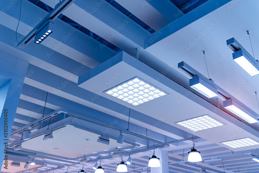 Obraz premium Directional LED lights on rails under the ceiling in a modern warehouse, shopping center building, office or other commercial real estate object.