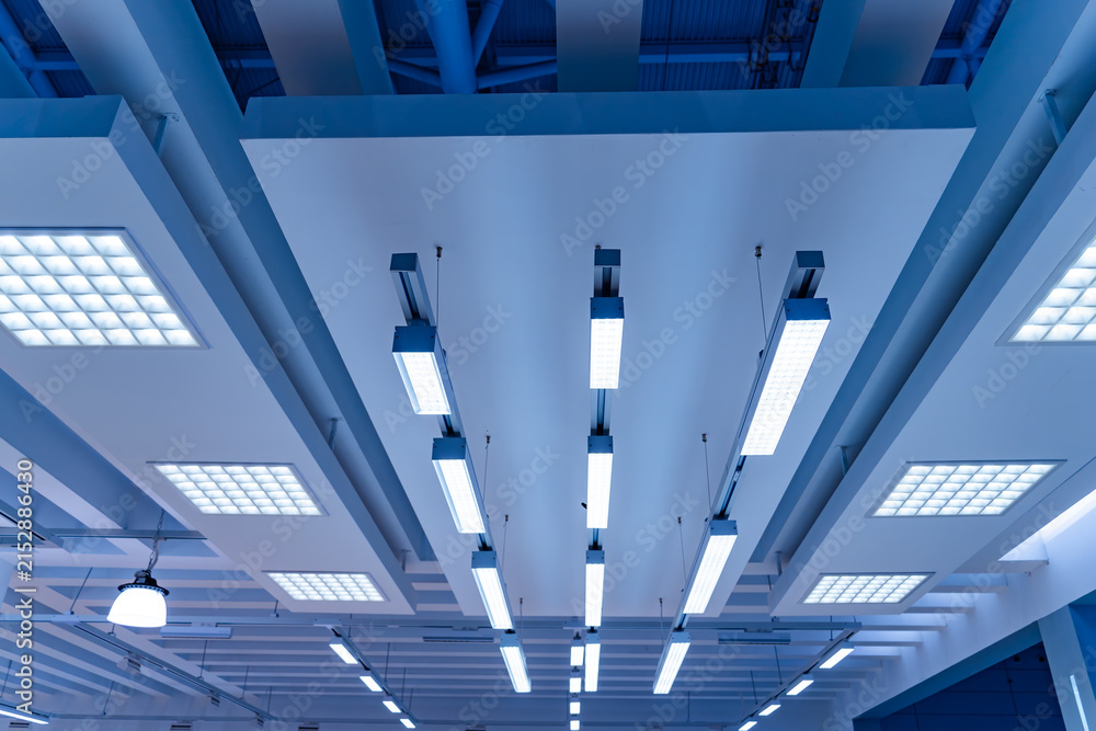 Naklejka premium Directional LED lights on rails under the ceiling in a modern warehouse, shopping center building, office or other commercial real estate object.