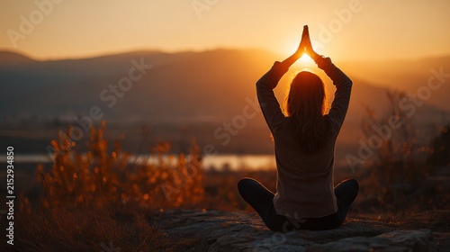 Back view of woman meditating in yoga pose catching sunset sun outdoors
