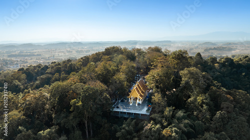 Canvas Print Wat Phra That Chom Kitti surrounded by dense green forest, overlooking the peaceful Chiang Rai countryside beneath a clear blue sky on 13 January 2023
