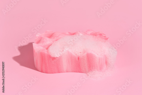 Obraz na płótnie Pink bath sponge with white soap suds and bubbles on a solid pink background, hy