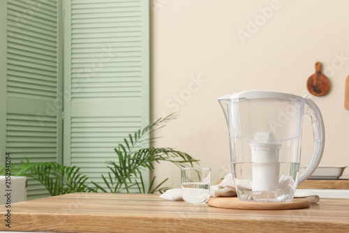 Fotografie Clear water filter pitcher and glass of purified drinking water on a wooden kitc