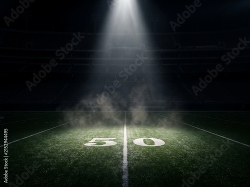 Illuminated football field with glowing fifty yard line under stadium lights