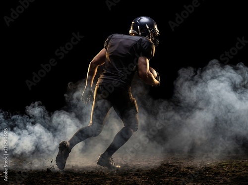 American football player running through smoke on dark field
