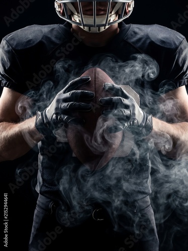 American football player holding ball with dramatic smoke effect