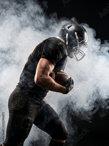 American football player in action holding ball with dramatic smoke effect