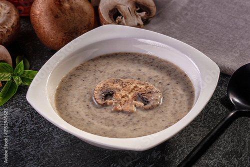 Fotografie Creamy mushroom soup in white bowl with sliced mushroom garnish and fresh basil