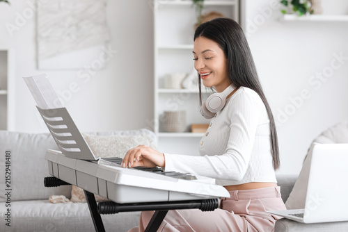 Young woman playing synthesizer on sofa at home