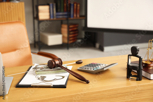 Judges gavel with handcuffs, money and clipboard on teachers table in classro...