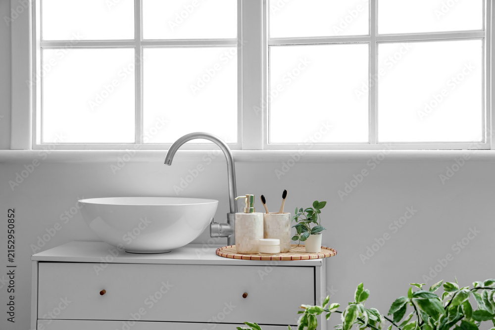 Fototapeta premium Cosmetic products with toothbrushes and houseplant near sink in bathroom