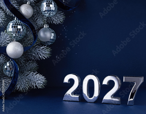 Festive New Year 2027 celebration background with shimmering silver baubles, glittering disco ball ornaments, and frosted pine branches on a deep blue backdrop