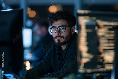 Software developer reviewing AI generated code on computer monitors in modern software engineering workspace