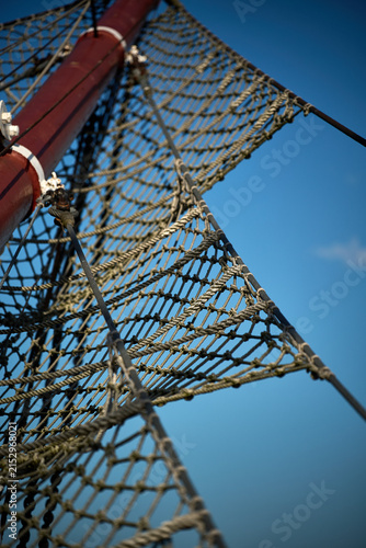Low angle view of rope netting and wooden mast rigging against blue sky, Gdynia, Pomerania, Poland, Europe