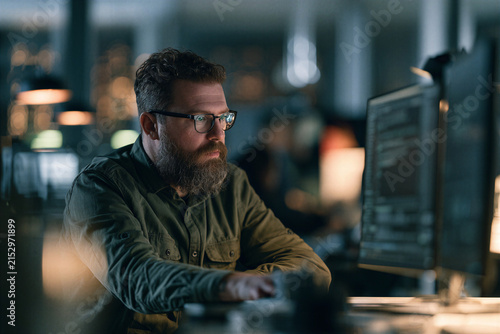 Data scientist analyzing artificial intelligence models on computer screens in modern research workspace