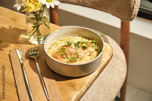 Obraz na plátně Creamy risotto with herb garnish served in bright sunlit interior