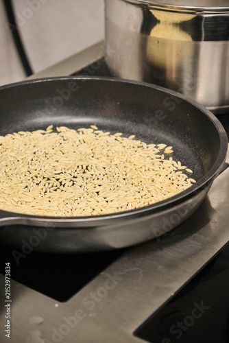 Foto Rice toasting in non-stick skillet on stovetop