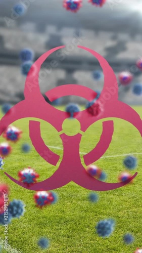 Biohazard symbol and Covid-19 cells against empty sports stadium