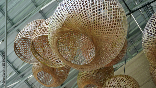 Cluster of woven rattan basket lamps hanging under industrial roof.