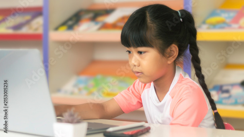 Focused Asian girl studying on laptop for online education and e-learning concept