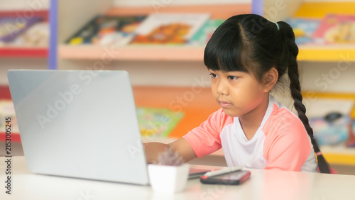 Focused Asian girl studying on laptop for online education and e-learning concept