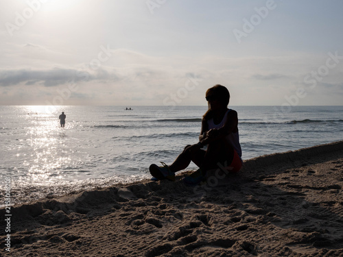 Obraz na płótnie Woman silhouetted against sun reflecting on ocean waves at dawn